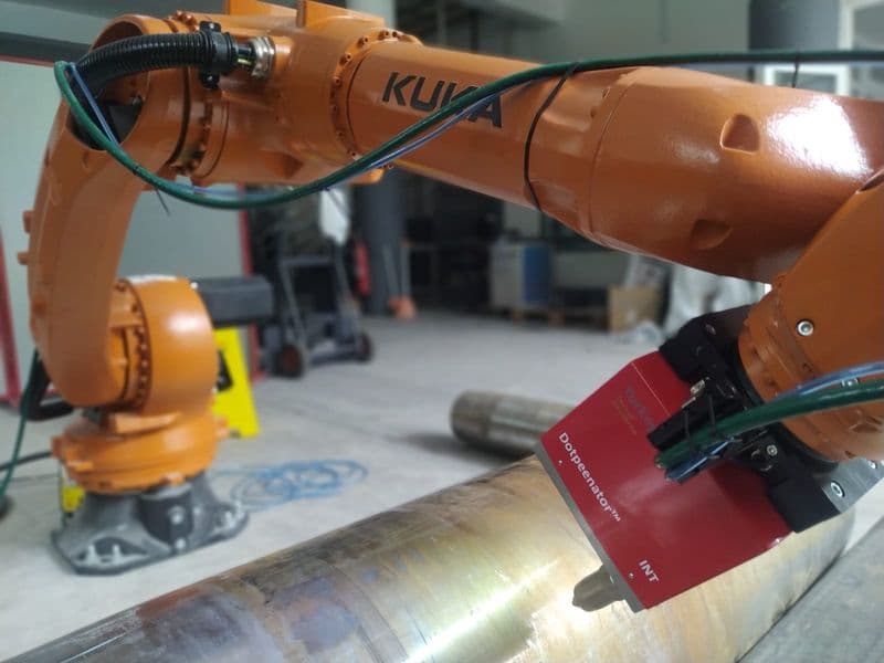 Markalama işlemi yapan KUKA robot koluna entegre Dotpeenator markalama kafası ve metal silindir.